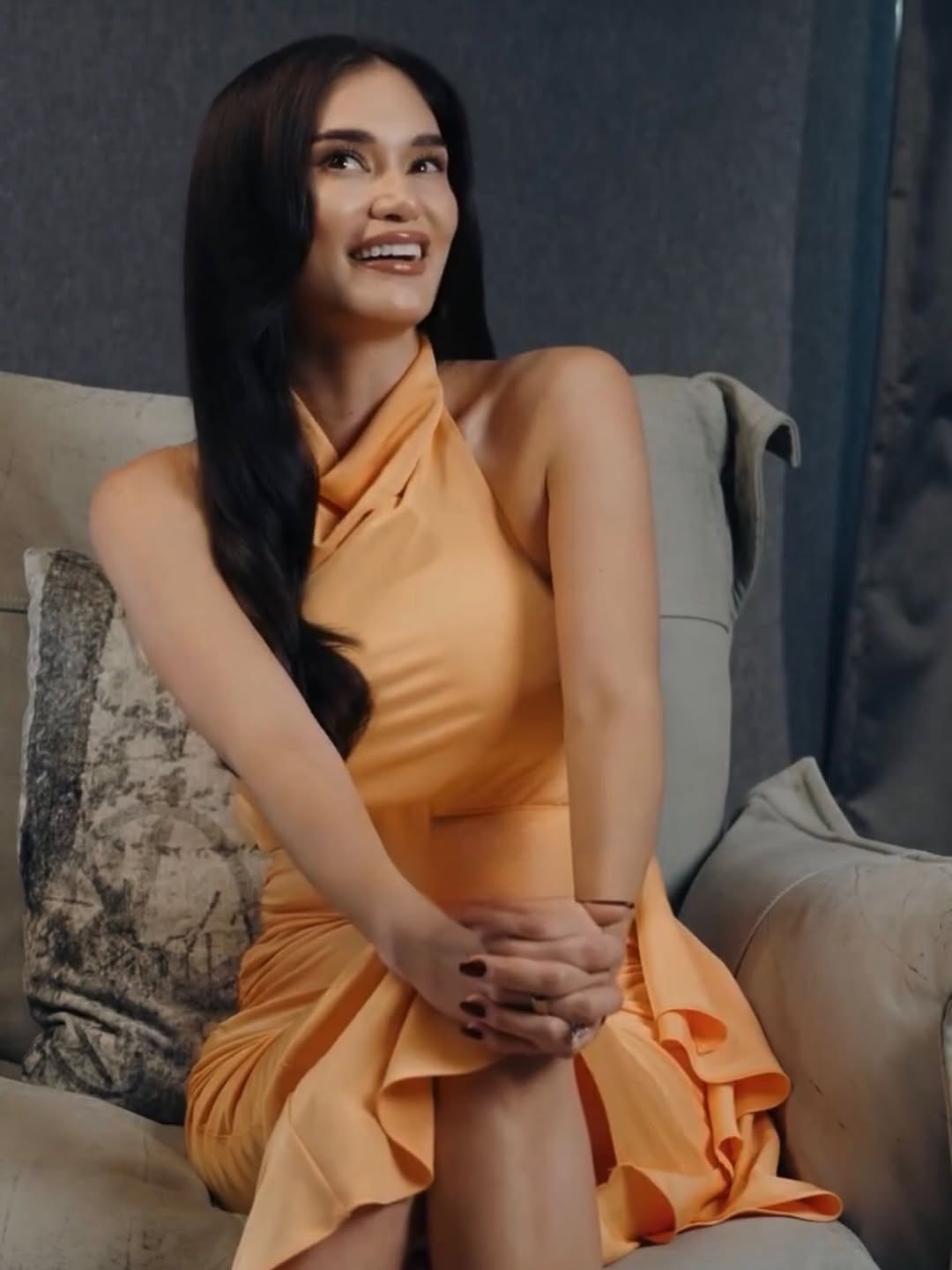 Pia Jaucey in peach halter dress, seated on grey sofa — Tatler Philippines editorial